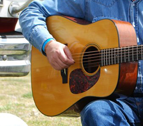 Photo of guitarist strumming an acoustic guitar.