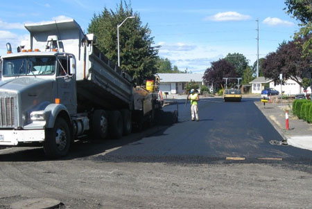 Photo of pavement maintenace crews pouring asphalt onto roadway