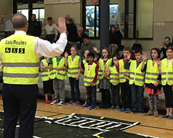 Children wear brightly colored safety vests and practice hand signals at a Safe Routes to School event.