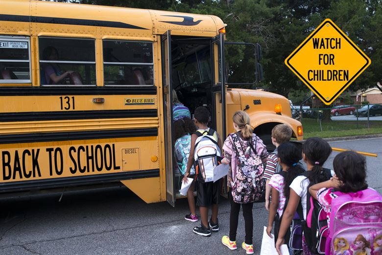 Elementary students in line to board a school bus.