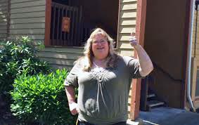 A woman smiles near her front door holding keys to her new home