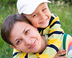 A smiling young boy gets a piggy back ride from his mom