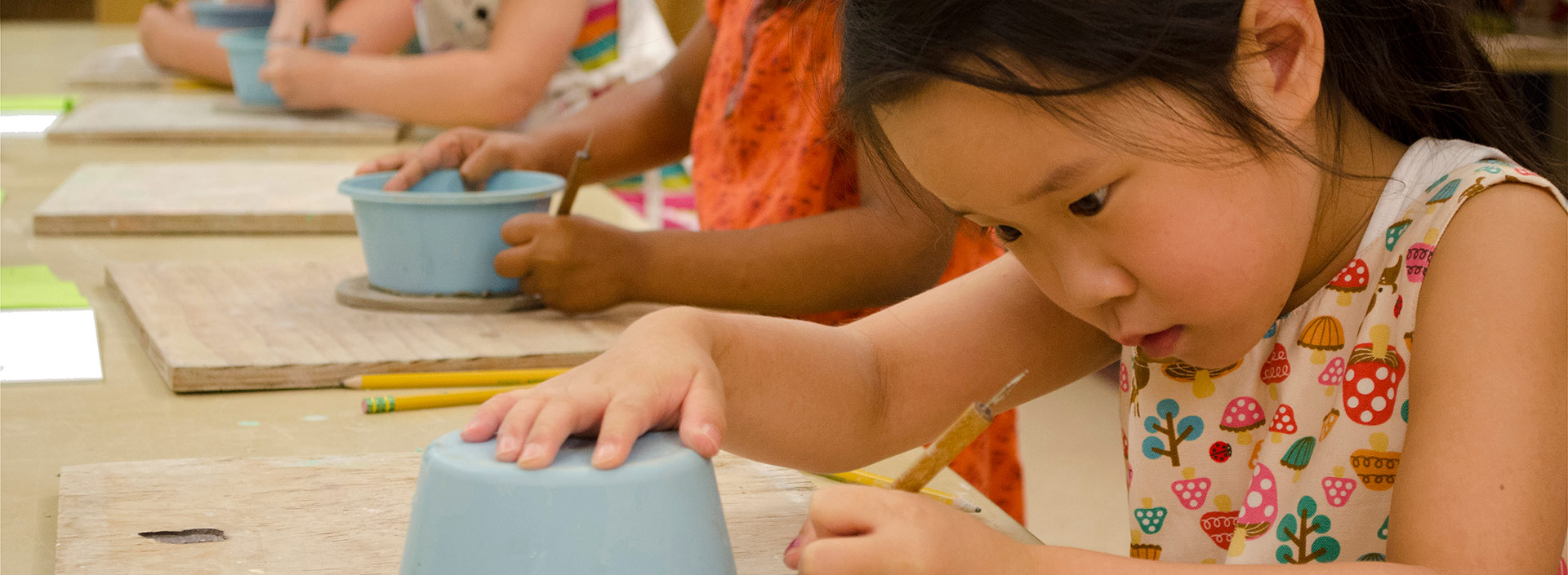 A young girl creating pottery in an art class