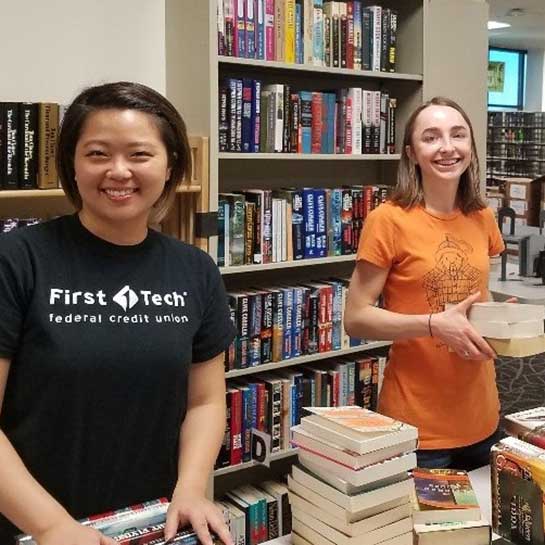 Two-volunteers-with-stacks-of-books