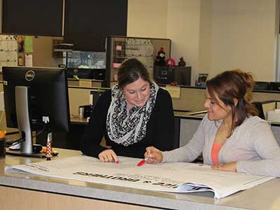 Two female employees look at building plans while working for the City of Hillsboro