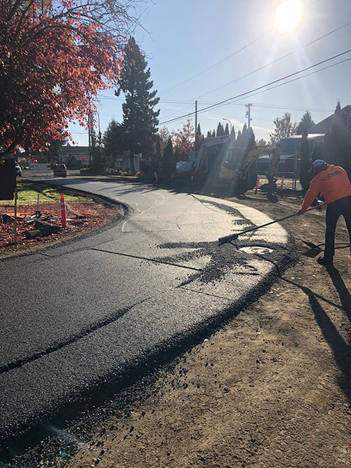 A Public Works employee smoothing fresh pavement