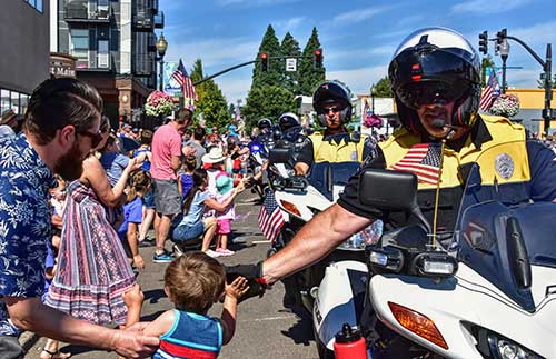 Traffic safety officers on motorcycles high five members of the crowd at a parade