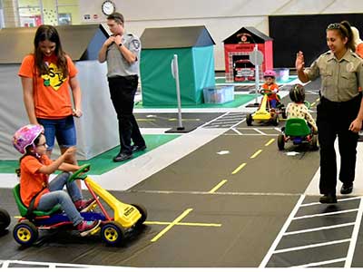 An Community Enhancement Team member directs children through the safety course at Safety Town