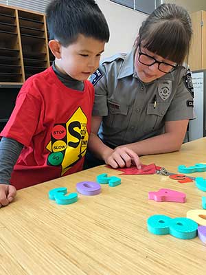 A child and Community Enhancement Team member do a table activity together at Safety Town