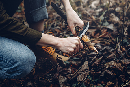 Man sharpening stick with knife.