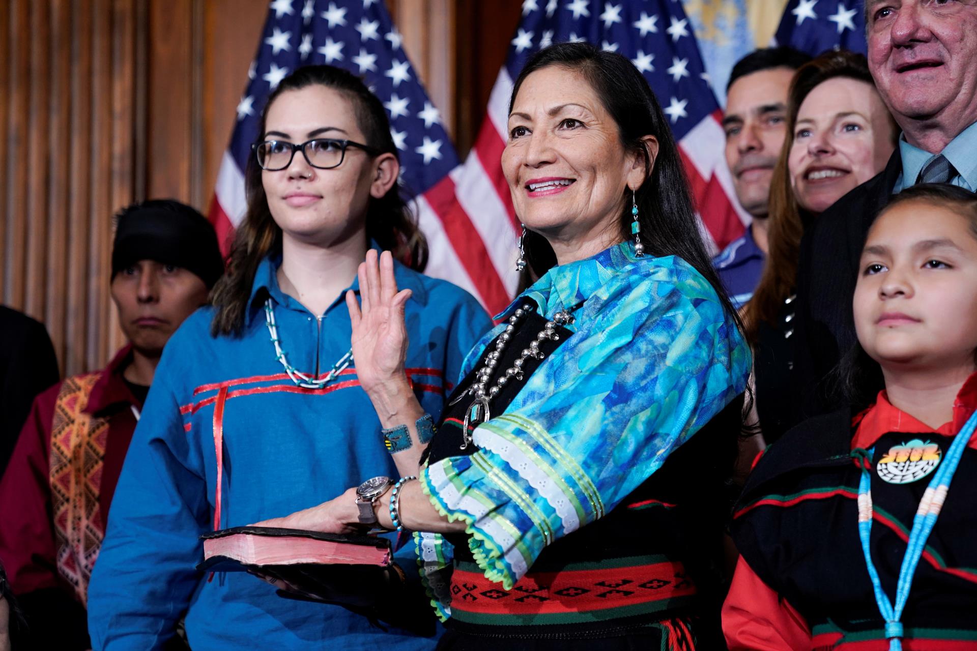 Deb Haaland raising right hand, with left hand on a book.