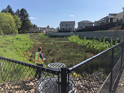 A Public Works employee inspects a private stormwater management facility