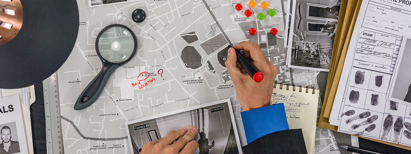 Maps, fingerprints, and case file information on a detective's desk