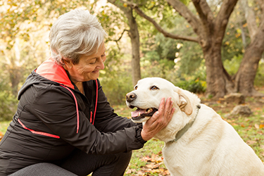 Senior Woman outside petting a dog.