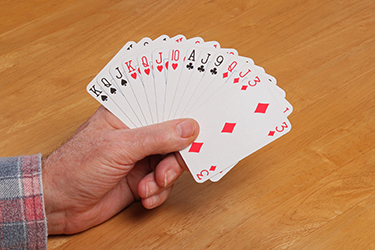 A man holding 13 cards in his hand.