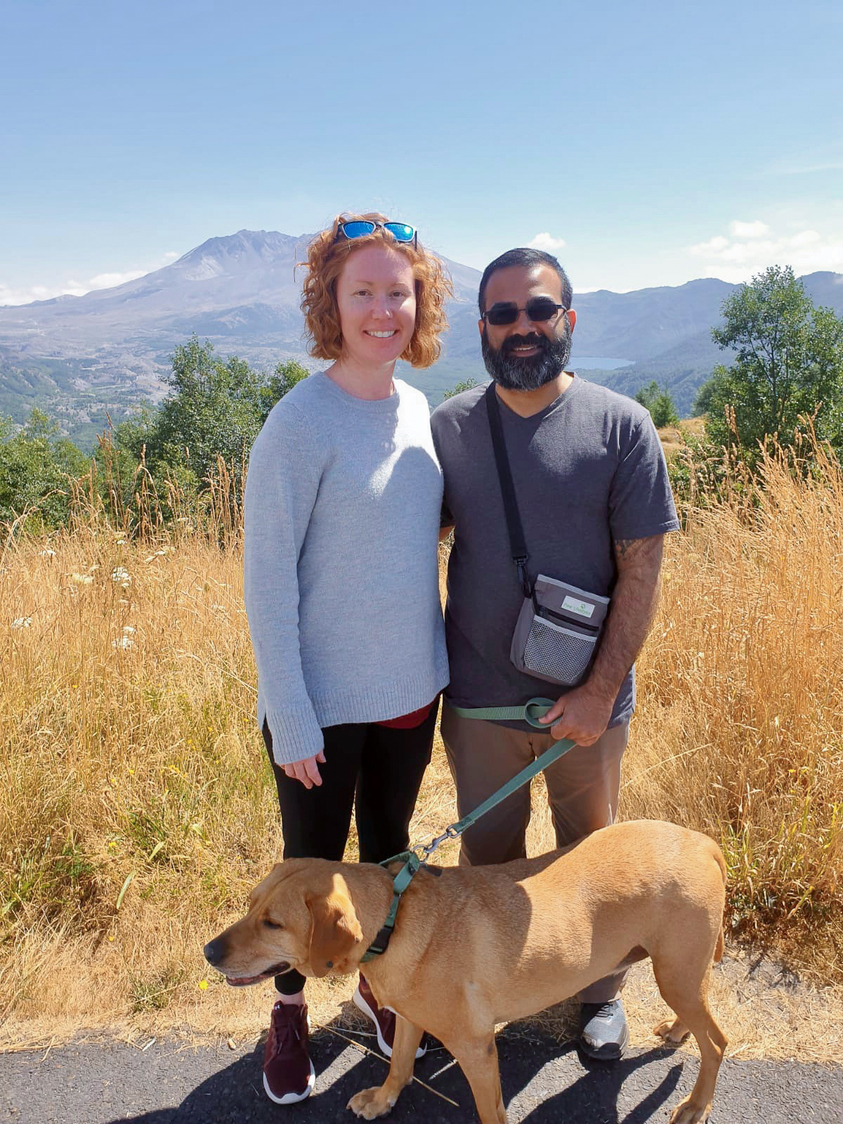 Rahim with his wife and their dog posing outdoors