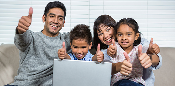 Family of four with laptop giving thumbs up