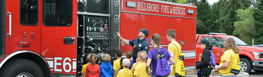 Fire fighter showing group of kids a fire truck