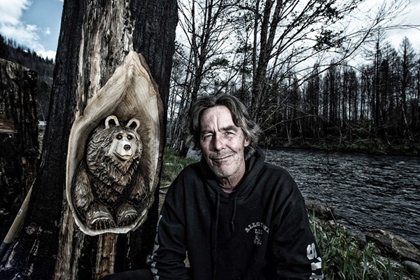 Man next to Bear Carving in burnt tree