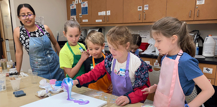 Children and instructor doing paint pouring at summer arts camp