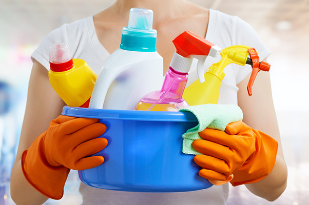 Woman holding a container full of cleaning supplies.