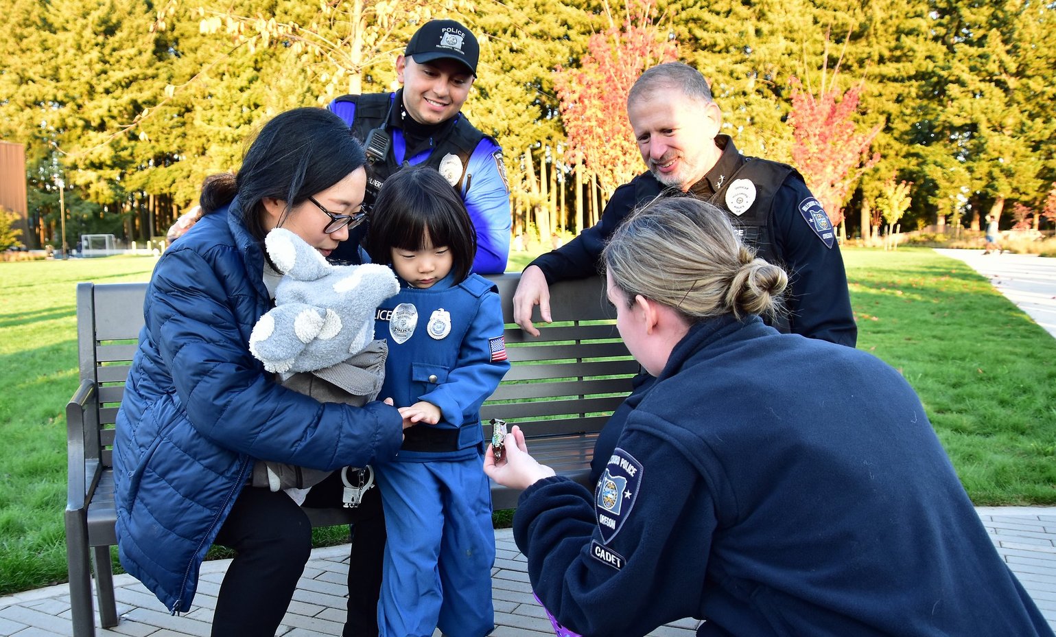 Hillsboro Police Chief Jim Coleman, a cadet, and an officer chat with a mother and child in a park