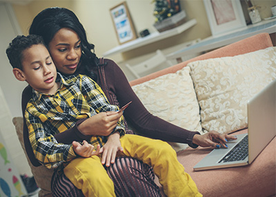 Parent child on laptop with library card in hand